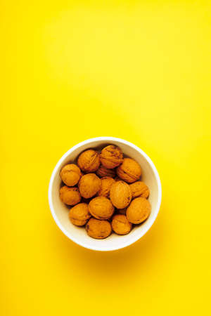 White bowl full of nuts on a yellow background.の写真素材