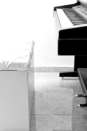 White seat in front of a black grand piano.の写真素材