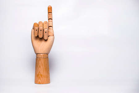 Orthopedic wooden hand on white background, raising index finger.の写真素材
