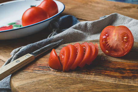 Tomatoes cut on a plate on a wooden kitchen table.の写真素材