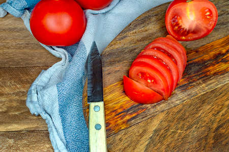 Tomatoes cut on a plate on a wooden kitchen table.の写真素材