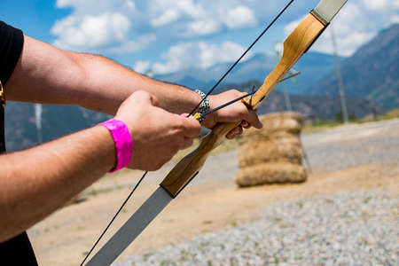 A person with a bow and an arrow aiming to shoot a bullseye.の写真素材