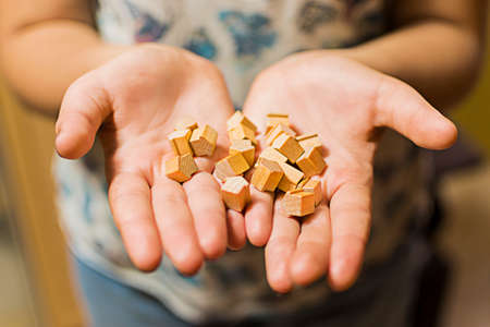 Woman's hands holding a pile of wooden toy houses.の写真素材