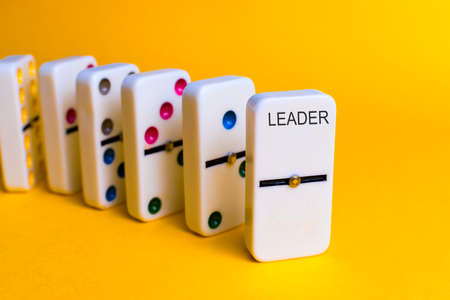 Dominoes that follow an order and a token as leader. Leadership concept