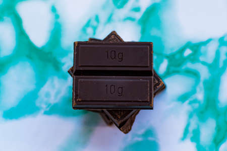 Ounce of ten grams of dark chocolate, on a background of blue marble.の写真素材