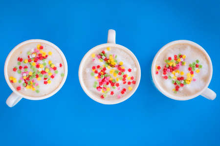 Party decorated coffee cups with foam and stars with blue background.の写真素材