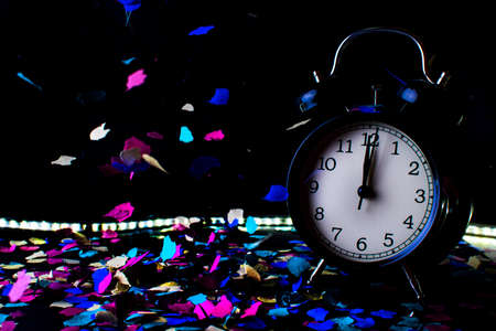 End of the year concept. Alarm clock with confetti with black background.の写真素材