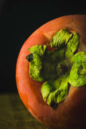 Portrait of a fresh persimon on wood with black background.の写真素材