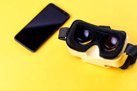 Yellow virtual reality glasses with mobile phone on a yellow backgroundの写真素材