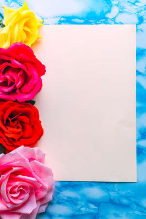 Invitation with roses of different colours and space to write, with blue marble background.の写真素材