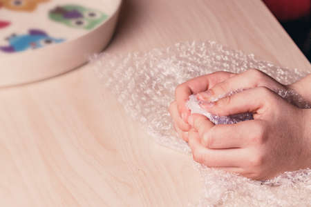 Stress concept. Woman's hands popping bubbles of a bubble paper on a table.の写真素材