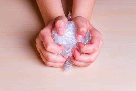 Stress concept. Woman's hands pressing hard on a bubble paper.