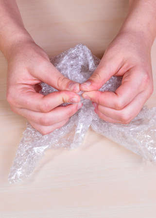Stress concept. Woman's hands popping bubbles of a bubble paper on a table.
