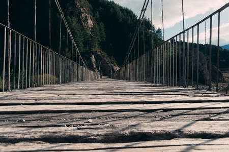 Wooden walkway of a suspension bridge seen from ground level.