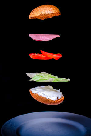 Toast with spread cheese, lettuce, tomato and sausage with black background.の写真素材