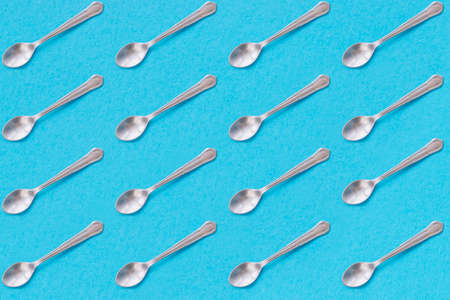 Metal dessert spoons with blue background. Repeat pattern.の写真素材