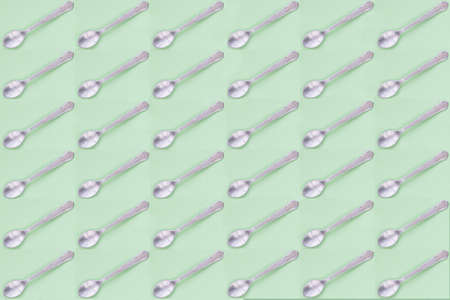 Metal dessert spoons with green background. Repeat pattern.の写真素材