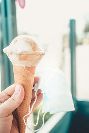New normality concept. Person holding an ice cream in his hand while holding a mask.