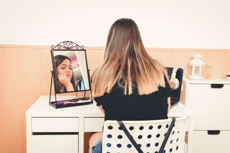 Reflection of the face of a teenager with a pensive face reflected in the mirror.の写真素材