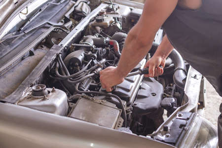 Mechanic working with a wrench on the car engine.