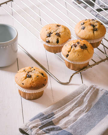 Group of homemade muffins with pieces of chocolate on a wooden table.