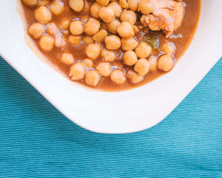 Mediterranean food concept. Food plate with chickpeas, vegetables and chicken pieces with blue cloth background.の写真素材