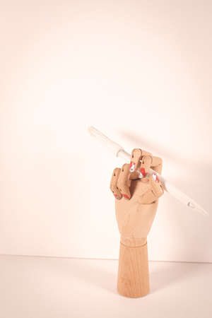 Wooden hand holding a white paintbrush on white background.の写真素材