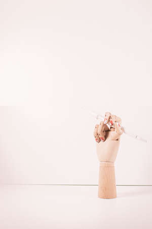 Wooden hand with a white paintbrush with white background.の写真素材