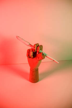 Wooden hand with a white paintbrush with red lightsの写真素材