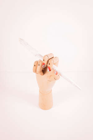 Wooden hand holding a white paintbrush on white background.の写真素材