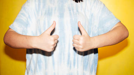 Woman in a tie dye shirt with thumbs up.の写真素材