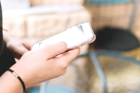 Woman's hands consulting information on her smartphone on a terrace.の写真素材