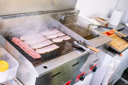 Food truck concept. Cook making a sausage and bacon on the grill.の写真素材