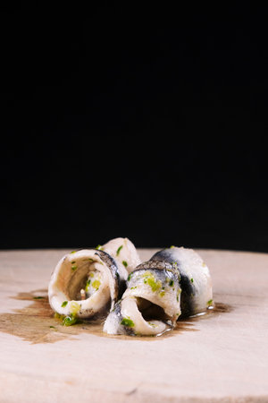 Piece of anchovy with garlic, parsley and oil on a chopping wood.の写真素材