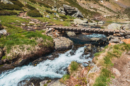 Wooden bridge over a river in the middle of the mountain.の写真素材