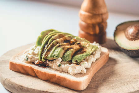 Slice of bread with avocado and cheese with pepper on a wood.の写真素材