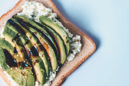 Close-up of a slice with cheese and avocado on a white plate.の写真素材