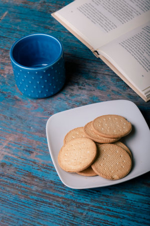 Cup of coffee with cookies and a book on a weathered wood.の写真素材