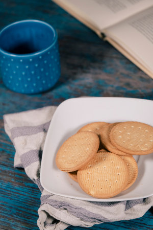 Cup of coffee with cookies and a book on a weathered wood.の写真素材