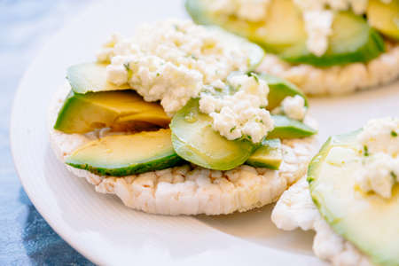 Breakfast of puffed wheat toast with avocado and fresh cheese.の写真素材
