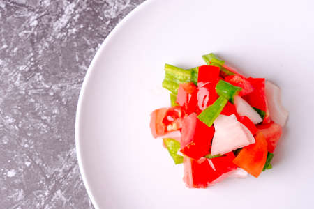 Mediterranean diet concept. Tomato, onion and green pepper mince on a white plate.の写真素材