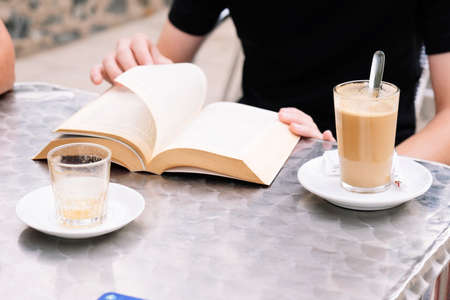 Teen boy with curly hair reading a book in a barの写真素材