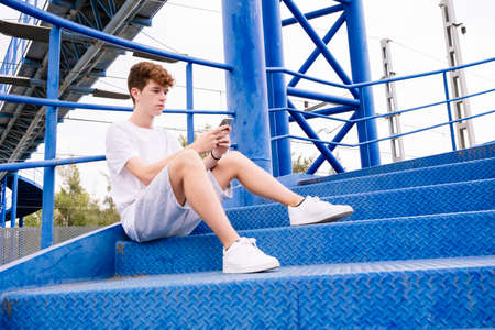 Teenager looking at the phone while waiting for someoneの写真素材