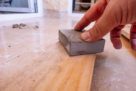 Hand sanding a wood with a sponge sandpaper.