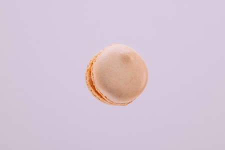 Peach macaron suspended in the air with purple background.の写真素材