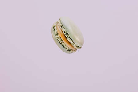 Pistachio colored macaron suspended in the air with purple background.の写真素材