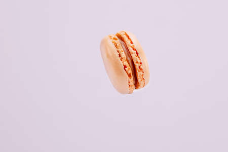 Orange macaron suspended in the air with purple background.の写真素材
