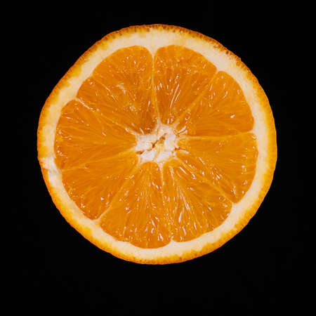 Half an orange levitating on black background.の写真素材