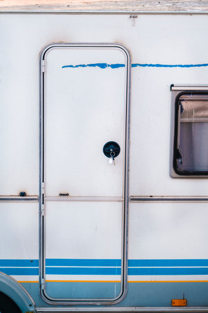 White door of an old caravan with blue stripes.の写真素材