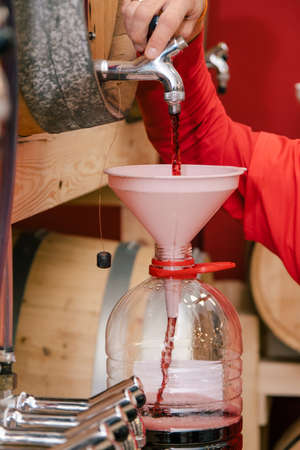 Man filling a bottle of wine in a cellar.